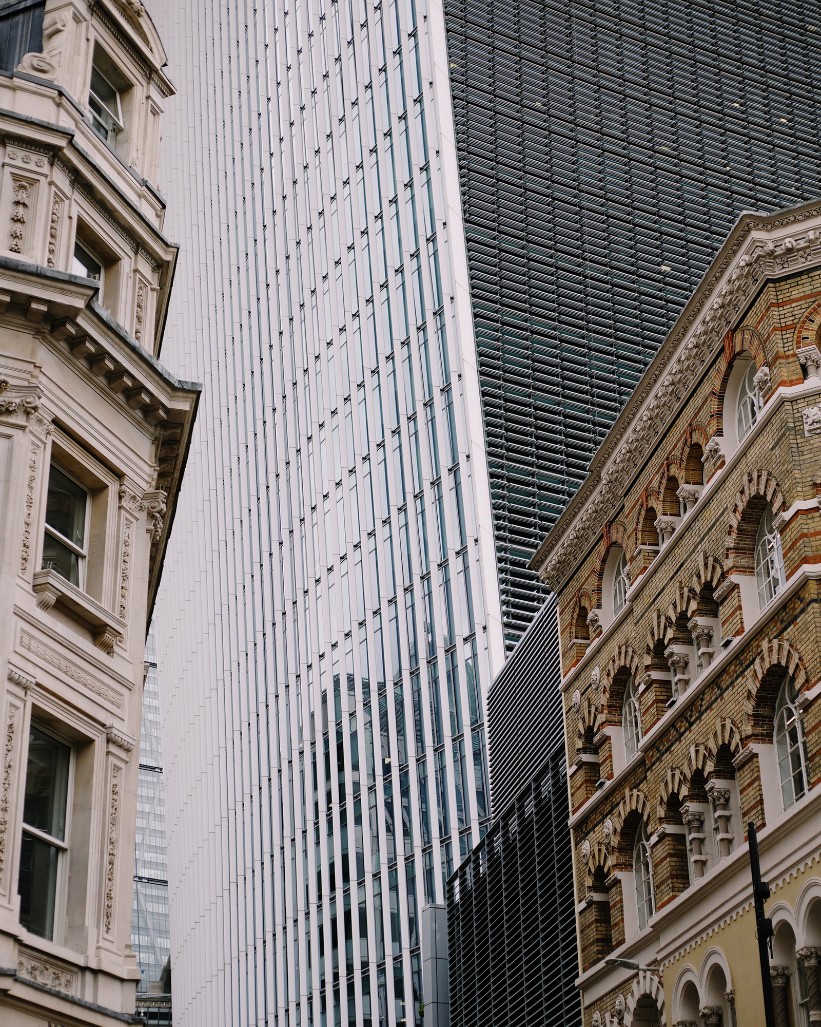 photograph of disparate architecture, sleek and reflective modern mixed with classical stone by Alice Angelini