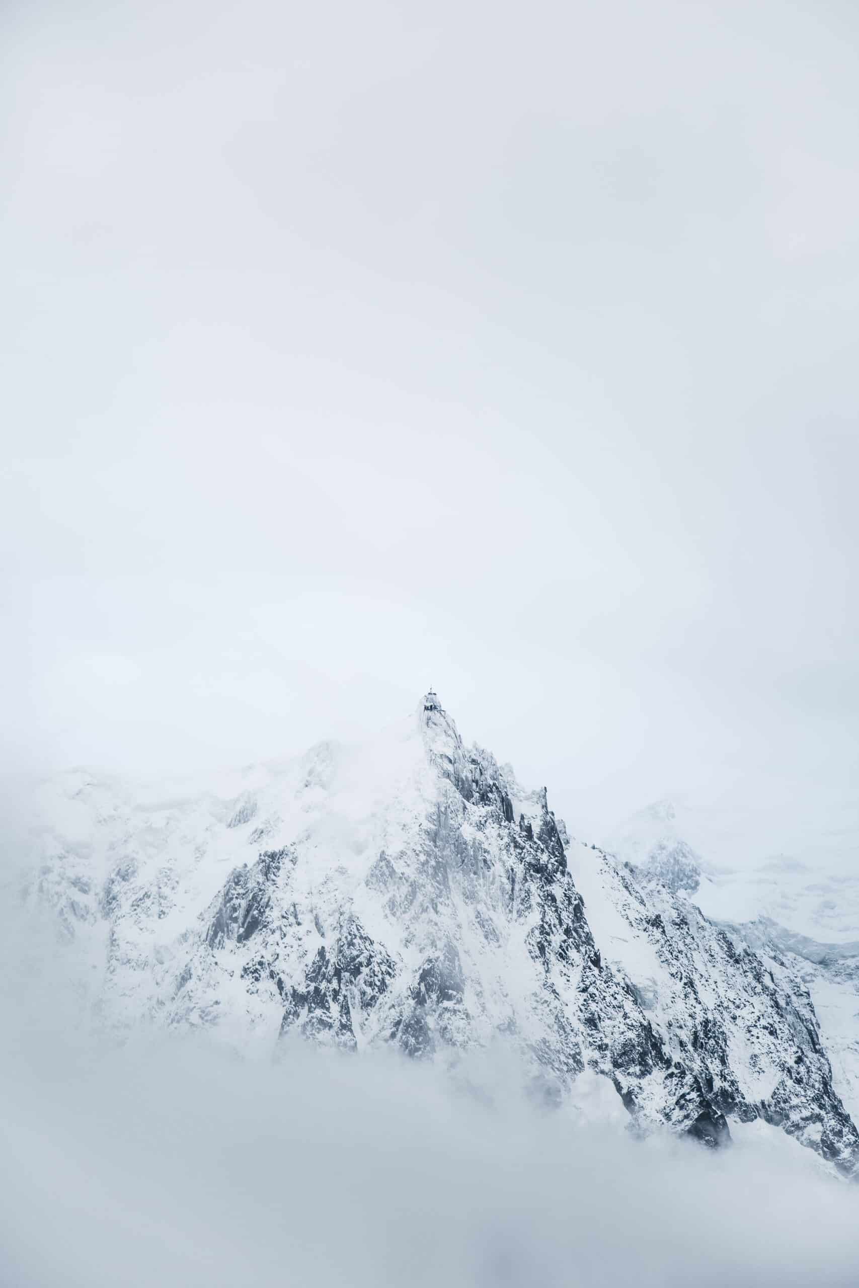 photograph of a craggy and snow-covered mountain surrounded by mists by Mayank Thammalla