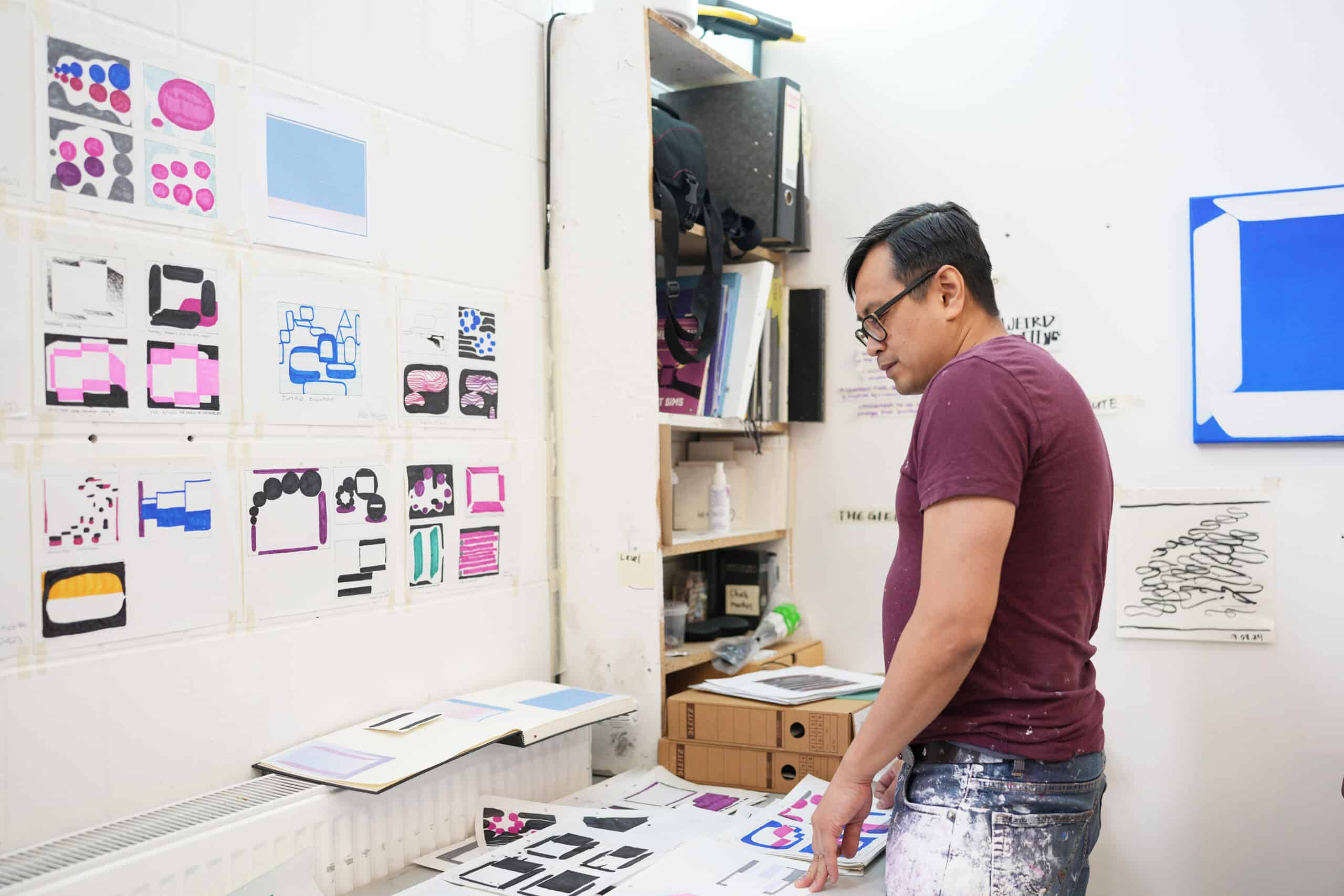 Nam Duc Nguyen looking at sketches by a tabletop in his Berlin studio.